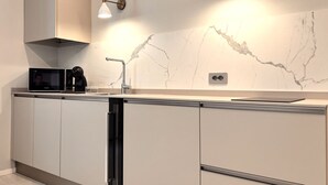 Uma cozinha moderna com micro-ondas embutido, pia e máquina de lavar louça.