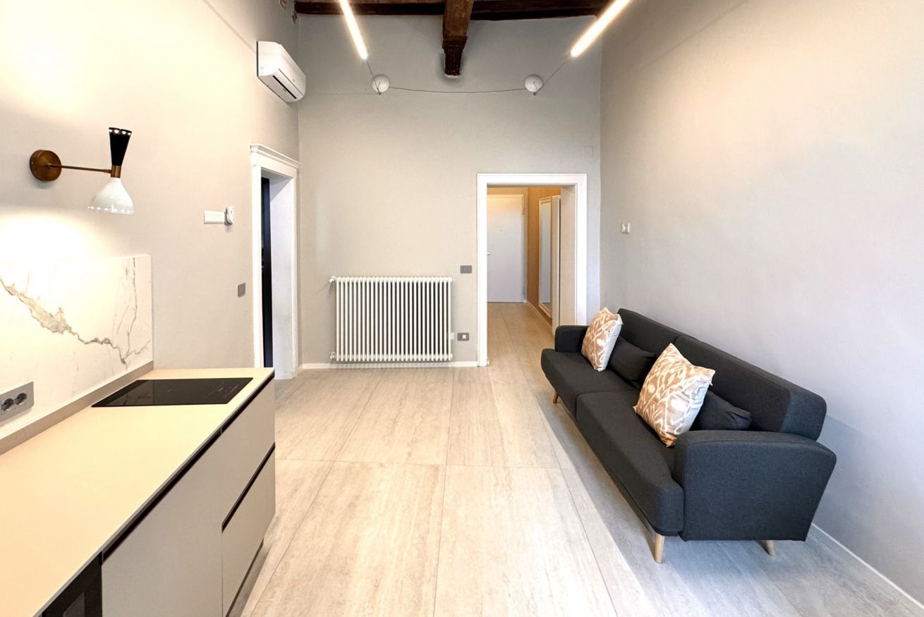Cocina moderna con estufa integrada, encimera blanca y lámpara fijada a la pared.