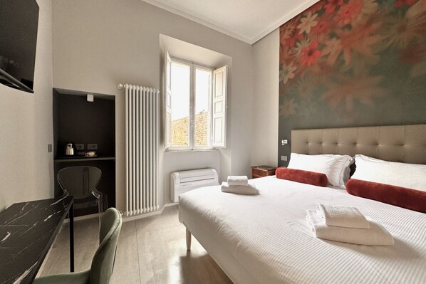 Ein Schlafzimmer mit Bett, Schreibtisch, Stuhl, Heizkörper und Fenster.