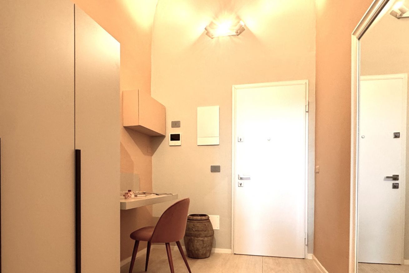 A compact kitchen with a dining area, a white door, and a small trash bin.