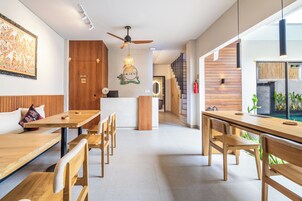 A modern dining area with wooden furniture, a ceiling fan, and a decorative wall hanging.