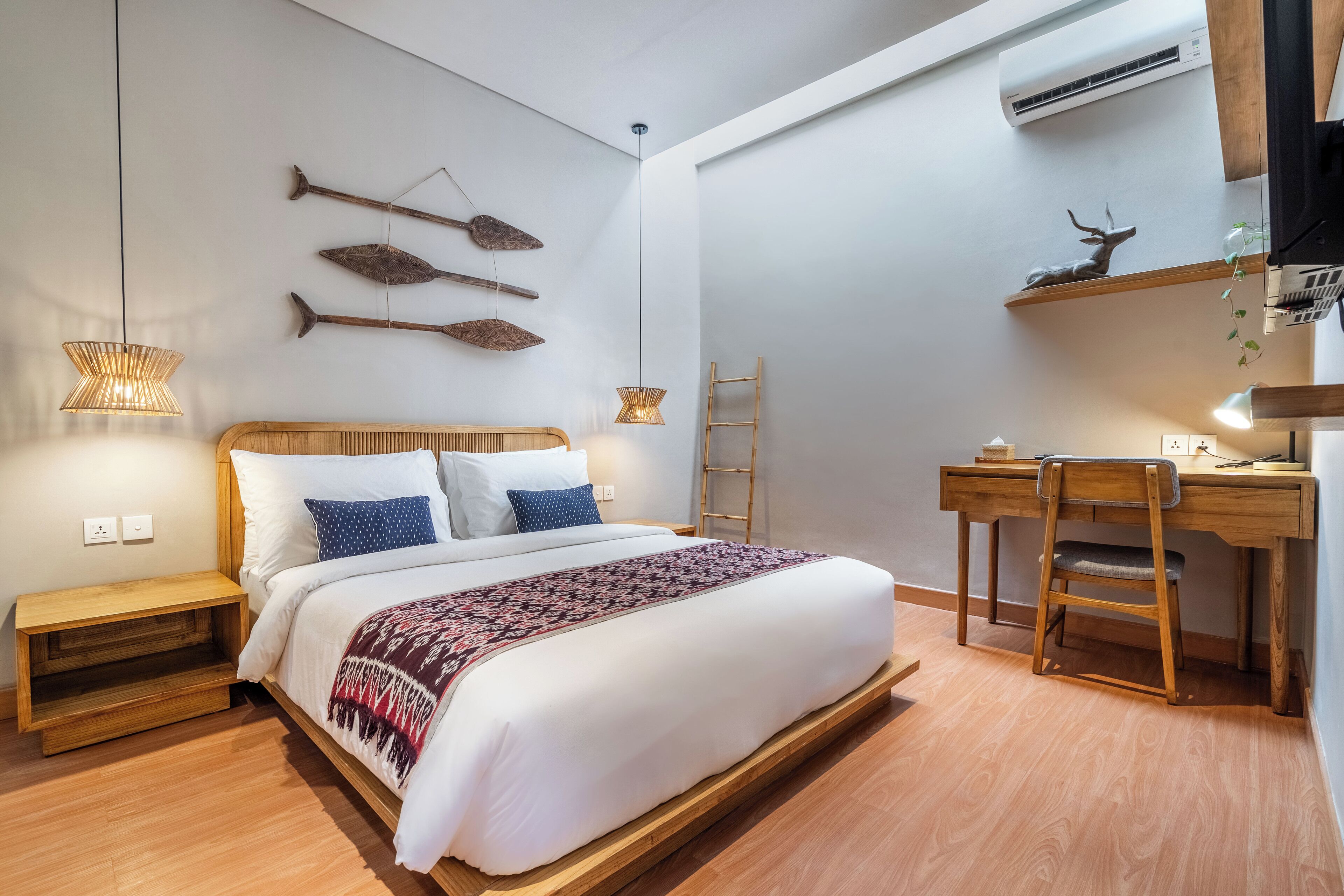 Un dormitorio con cama de madera, mesitas de noche, un escritorio con silla y decoración en la pared.