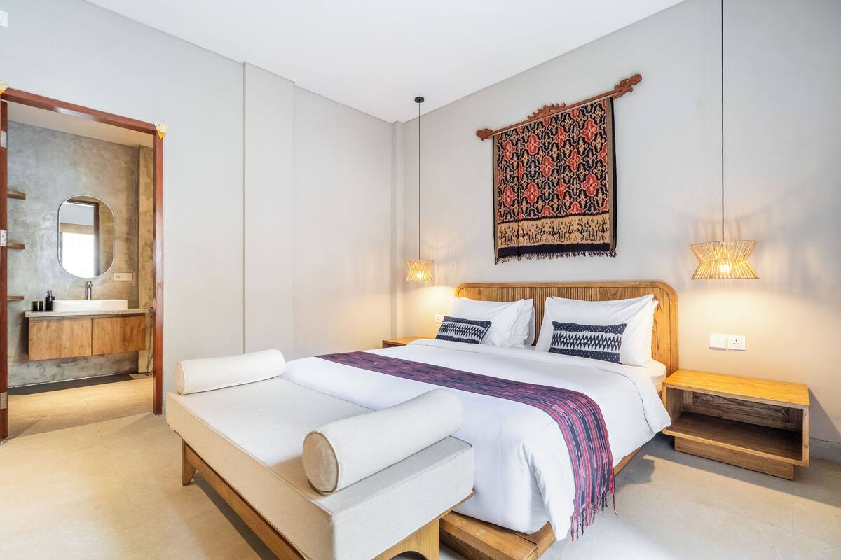 A modern bedroom with a large bed, wooden headboard, and a small bedside table.