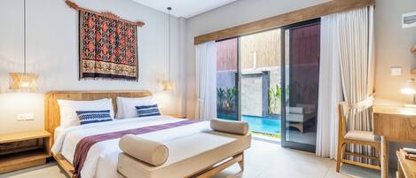 A modern bedroom with a large bed, a desk, and a view of a pool.