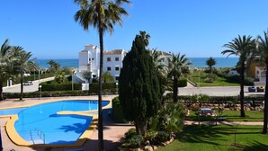 A resort with a swimming pool, palm trees, and a view of the sea. - Anacasa San Fernando MET Oliva Nova AP642 (Oliva)