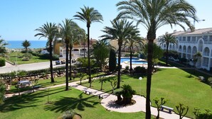 A resort with a swimming pool, palm trees, and a view of the sea. - Anacasa San Fernando MET Oliva Nova AP642 (Oliva)