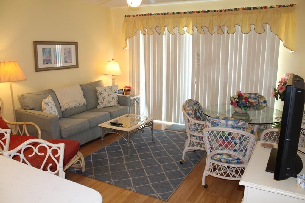 A living room with a sofa, a coffee table, and a dining area with chairs and a table.