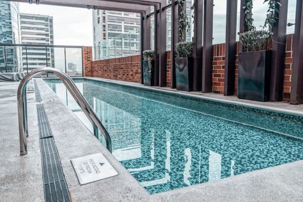 Una piscina interior moderna con agua cristalina, rodeada de paredes de ladrillo y barandillas de metal.