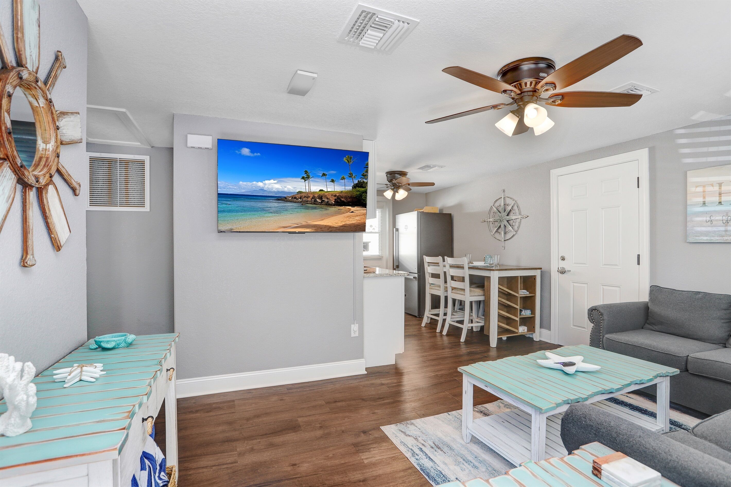 A living room with a gray sofa, a teal coffee table, and a ceiling fan.