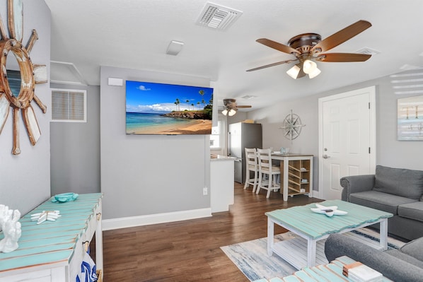 A living room with a gray sofa, a teal coffee table, and a ceiling fan.