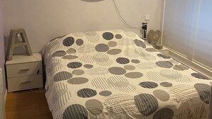 Een slaapkamer met een bed, nachtkastje, lamp en een rond decoratie aan de muur.