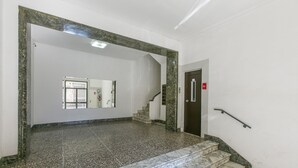 Un vestíbulo con suelo de mármol y una escalera que da a un ascensor.