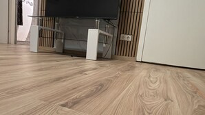 Ein Zimmer mit Holzboden, einem Fernseher auf einem Schrank und einer weißen Wand mit Steckdose.
