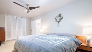 Une chambre à coucher comprenant un lit, un ventilateur de plafond, une armoire et un élément décoratif mural.