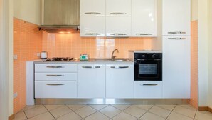 A kitchen with white cabinets, a stove, an oven, and a sink.