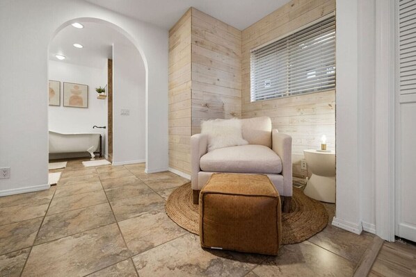A modern living room with a beige sofa, a round woven rug, and a wooden accent wall.