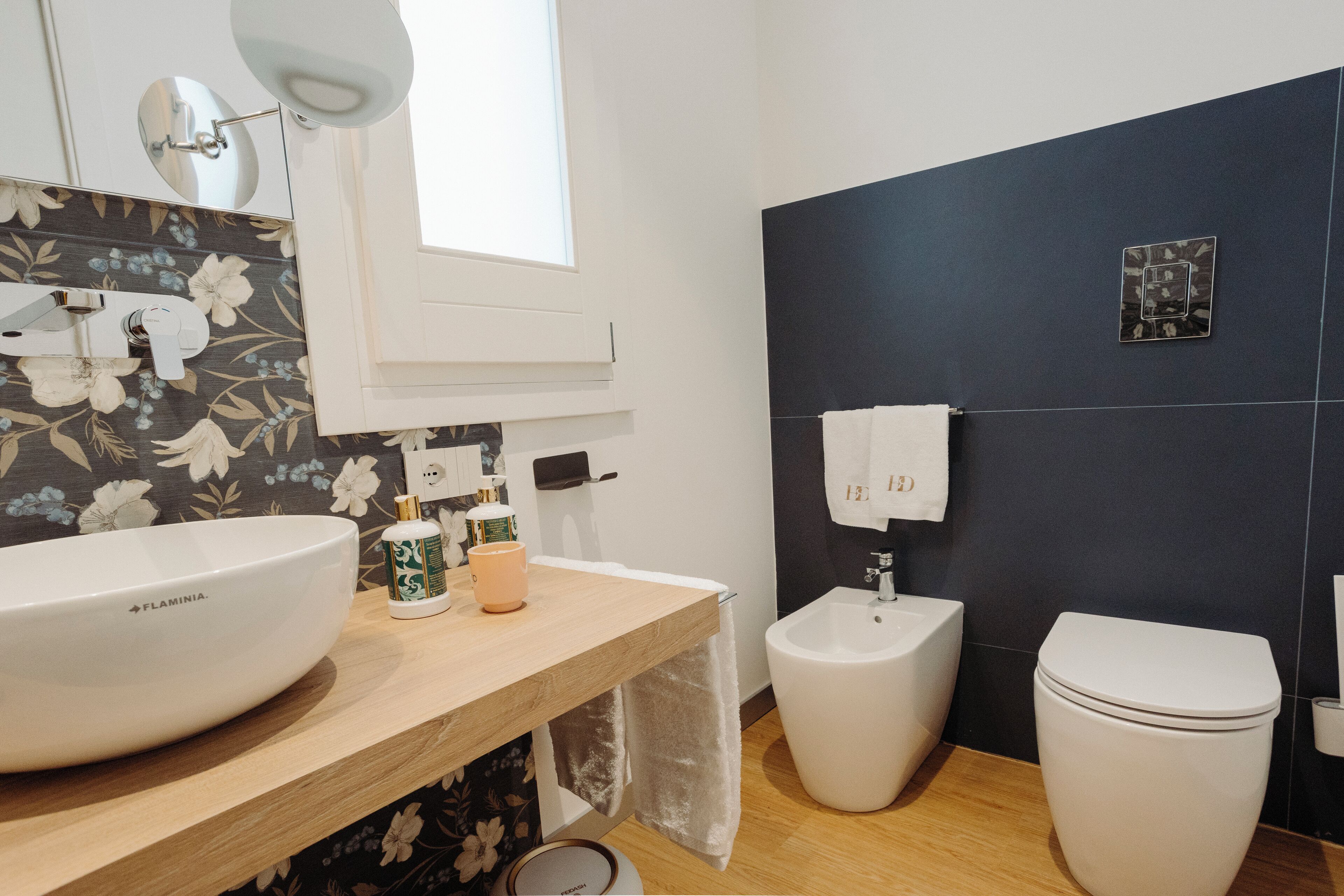 A modern bathroom with a large white sink, a bidet, and a toilet.