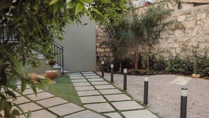 Un vialetto lastricato con bordi in erba che conduce a un edificio con una parete in pietra e una scalinata.