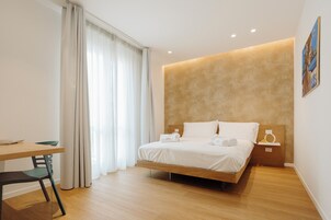 Una habitación de hotel moderna con una cama de madera, una mesita de noche pequeña, un escritorio y una silla.