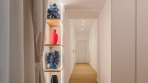 Un corridoio con pavimento in legno, pareti bianche ed scaffali con vasi decorativi.