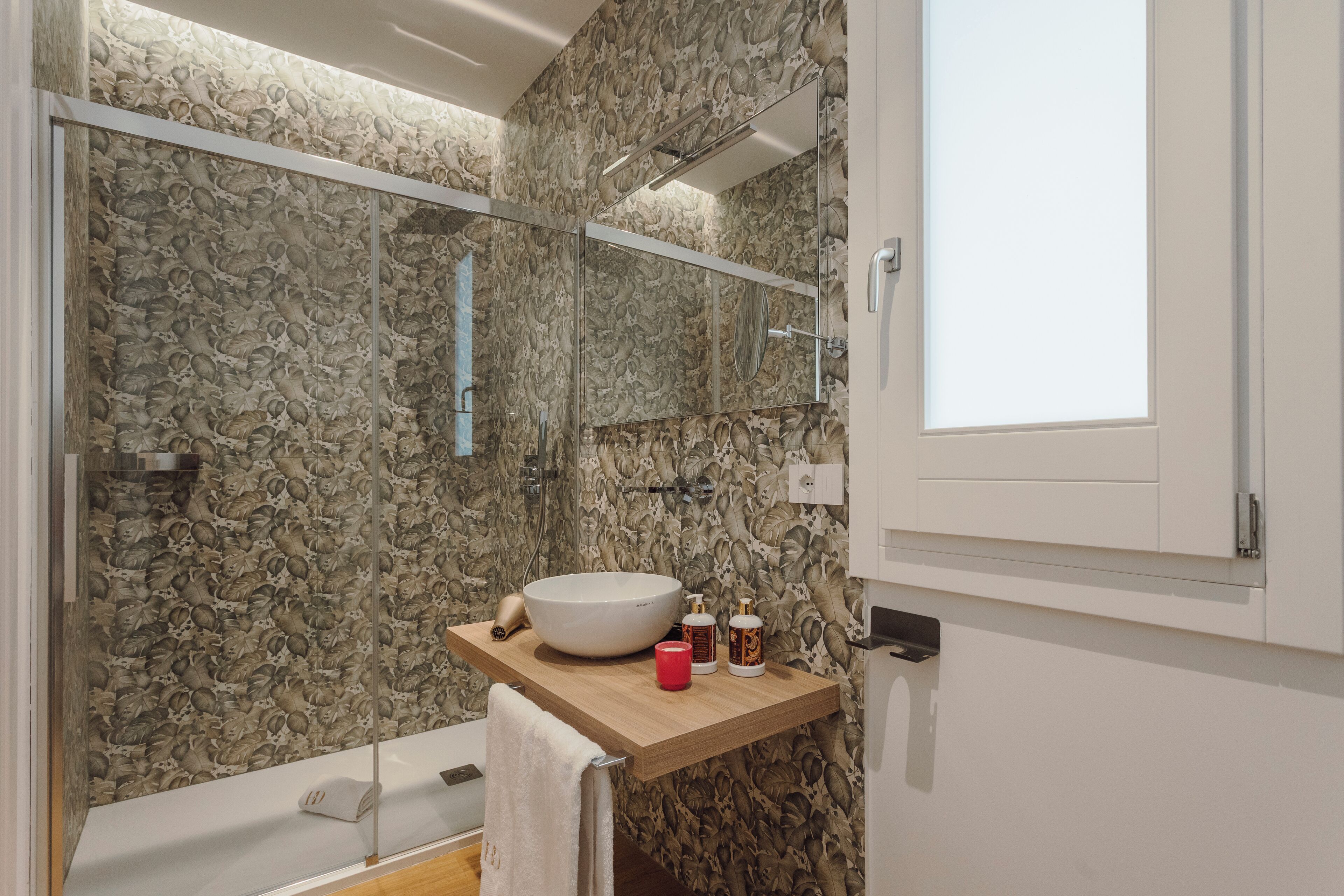 Une salle de bain avec un grand miroir, un lavabo et une douche.