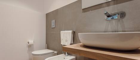 Un baño moderno con un lavamanos grande tipo recipiente, un bidé y un inodoro.