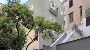 Un edificio moderno con facciata grigia, una scalinata e un albero nel cortile.