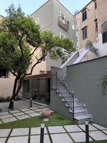 Un edificio moderno con fachada gris, una escalera y un árbol en el patio.