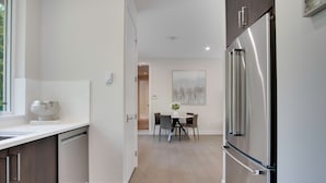 Una cocina moderna con lavavajillas, refrigerador y comedor con mesa y sillas.