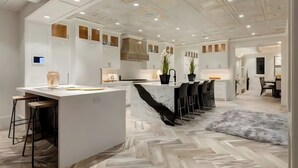 Eine moderne Küche mit einer zentralen Kochinsel, Barhocker und einem Essbereich mit Stühlen.