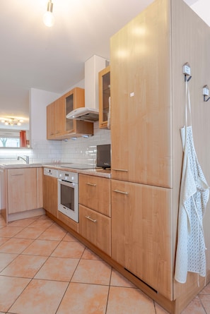 Eine moderne Küche mit Holzschränken, einem eingebauten Ofen und einer weißen Arbeitsplatte.