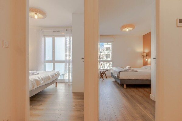 A hotel room with a bed, a desk, and a view of the outside.
