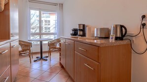 A compact kitchen with a dining area, featuring a coffee maker, kettle, and a small table with chairs. - Cassio (Annecy)