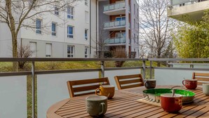 A wooden table with chairs on a balcony, surrounded by a railing. - Cassio (Annecy)