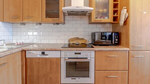 A kitchen with wooden cabinets, a dishwasher, an oven, and a microwave. - Cassio (Annecy)