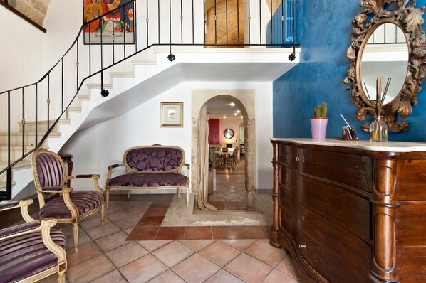 A grand staircase leading to an upper floor, a dining area with a red accent wall, and a large ornate mirror. - Prince 25 - Lecce Selection (Lecce)