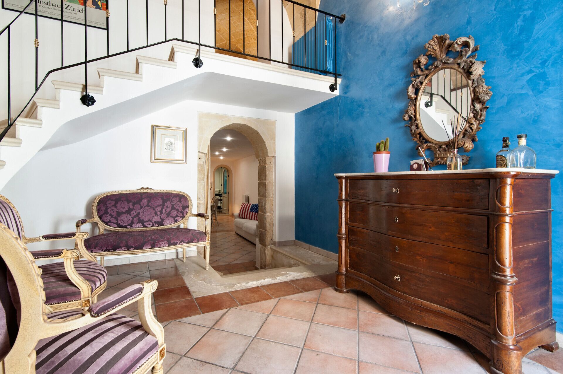 A spacious living area with a staircase, a large mirror, and a wooden dresser.