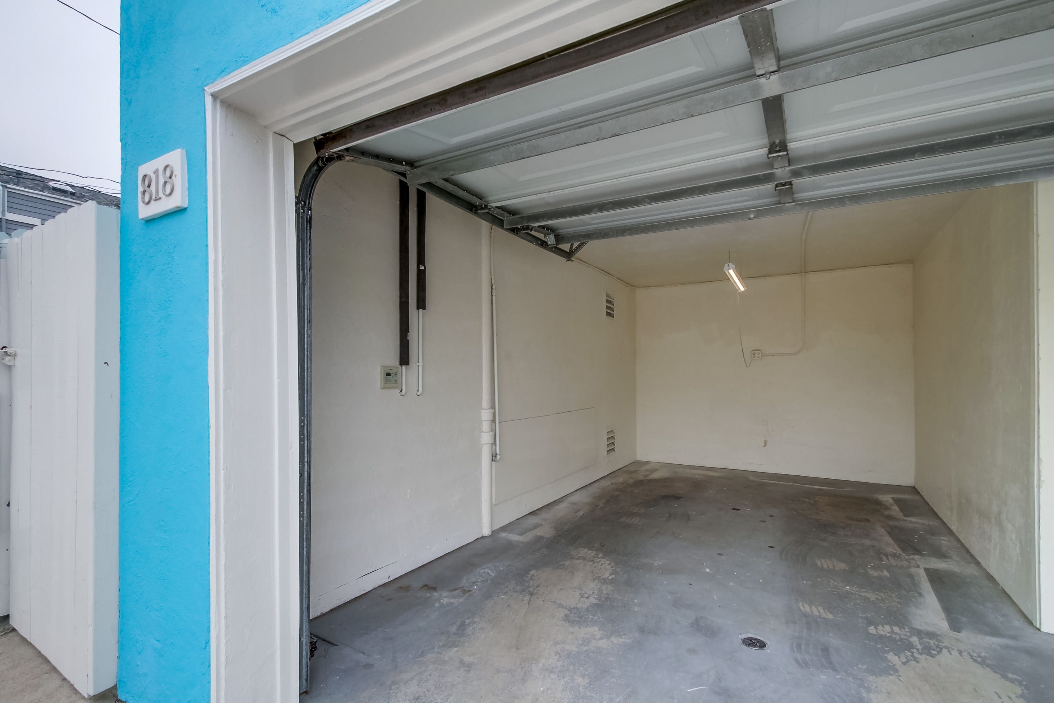 A garage with a white door, a blue wall, and a number 818 sign.