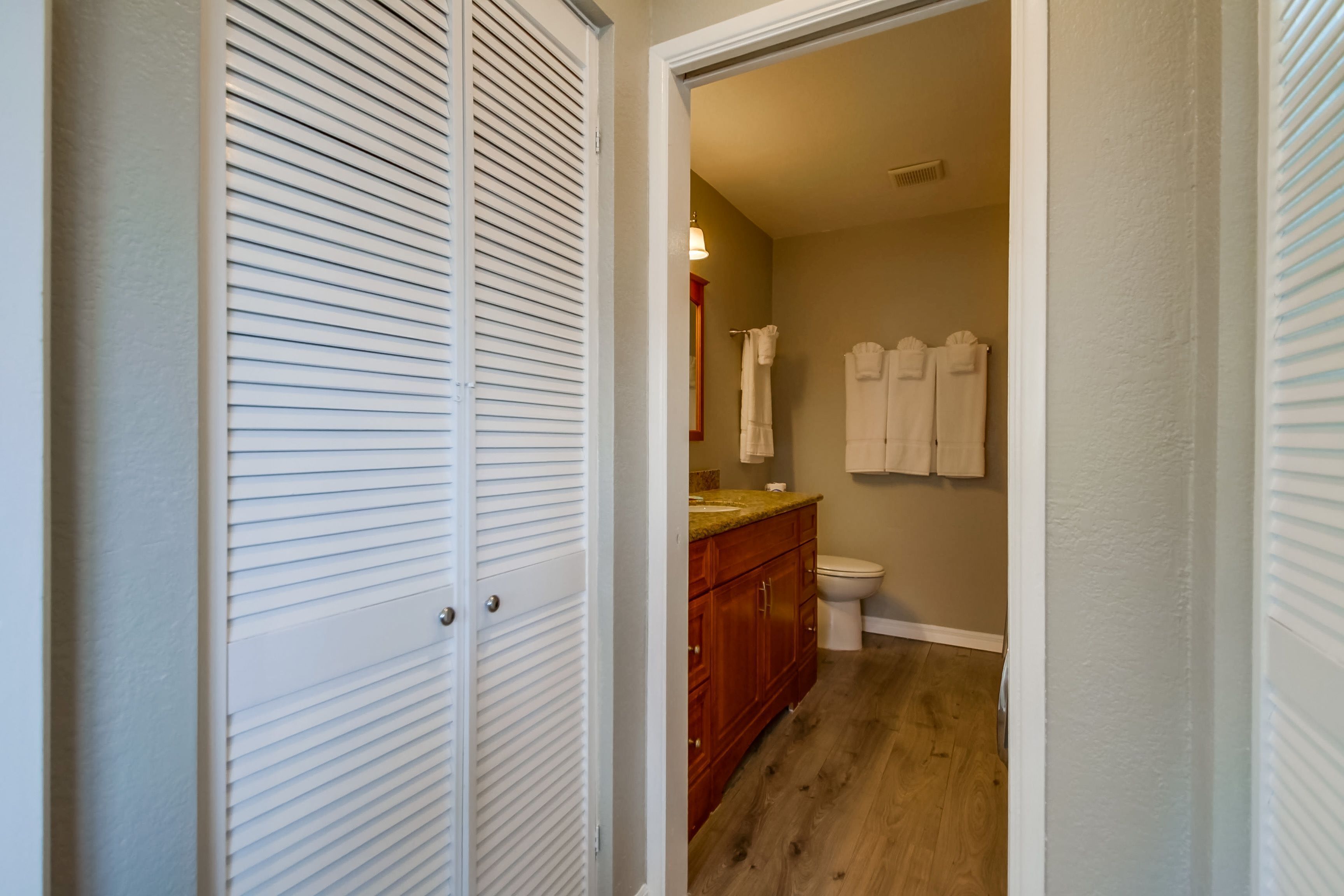 A bathroom with a wooden vanity, a toilet, and a towel rack.