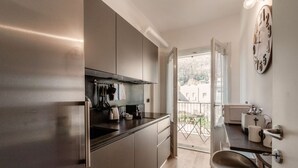 A modern kitchen with stainless steel appliances, a bar stool, and a view of the outdoors.