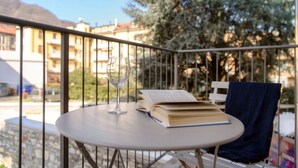 A round table with a book and a glass on it, a chair with a towel, and a balcony railing.