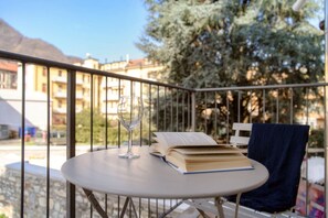 A round table with a book and a glass on it, a chair with a towel, and a balcony railing. - Minerva - MyHomeinComo (Como)