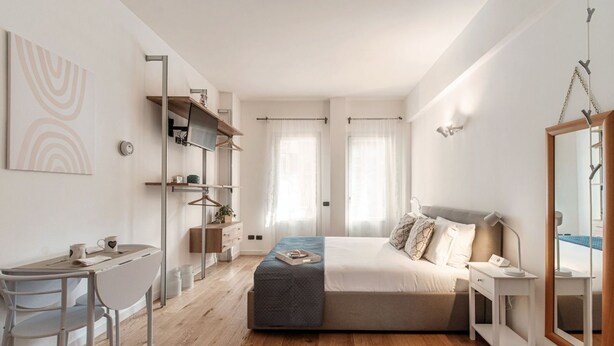 A modern bedroom with a bed, bedside table, and a desk with a chair.