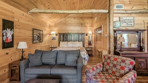 A cozy log cabin interior with a bed, sofa, armchair, and a sign reading "on mountain time". - #74 Pinewood Cabin: Hog Holler (Mountain View)