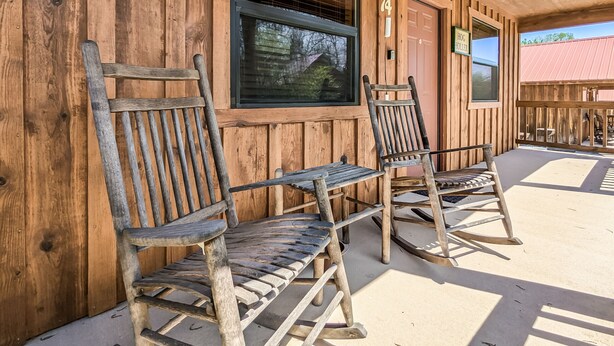 A wooden building with a porch, two rocking chairs, and a window with blinds. - #74 Pinewood Cabin: Hog Holler (Mountain View)