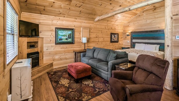 Ein gemütliches Blockhauszimmer mit einer Couch, einem Sessel und einem Bett.