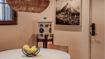 Un coin repas avec une table ronde, un saladier de fruits, une lampe décorative suspendue, un récipient en céramique de style japonais traditionnel et un tableau encadré représentant le mont Fuji.