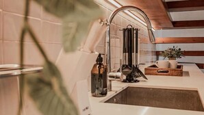 Una cocina moderna con un lavamanos de acero inoxidable, hervidor de agua y cafetera.