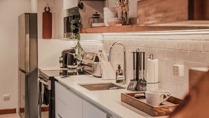 Una cocina moderna con un refrigerador de acero inoxidable, una cafetera y un lavamanos.