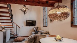 Un espacio habitable moderno con una escalera, un comedor con una mesa redonda y una lámpara de fibras naturales grande.